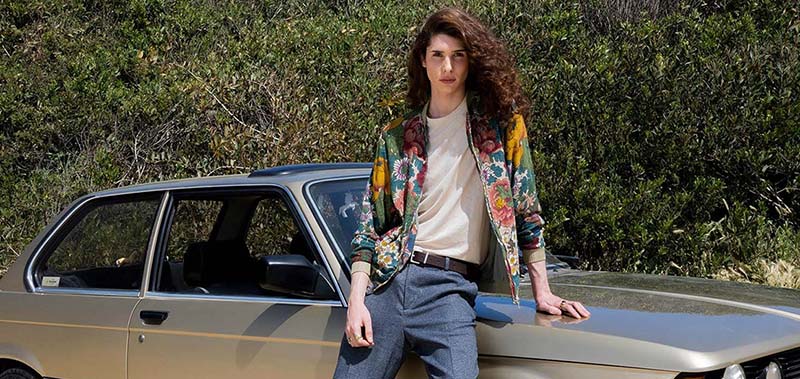 Tânăr chipeș aplecat în fața unei mașini.