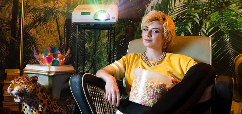 O tânără pe nume Leyla stă relaxată pe un scaun cu floricele de porumb.